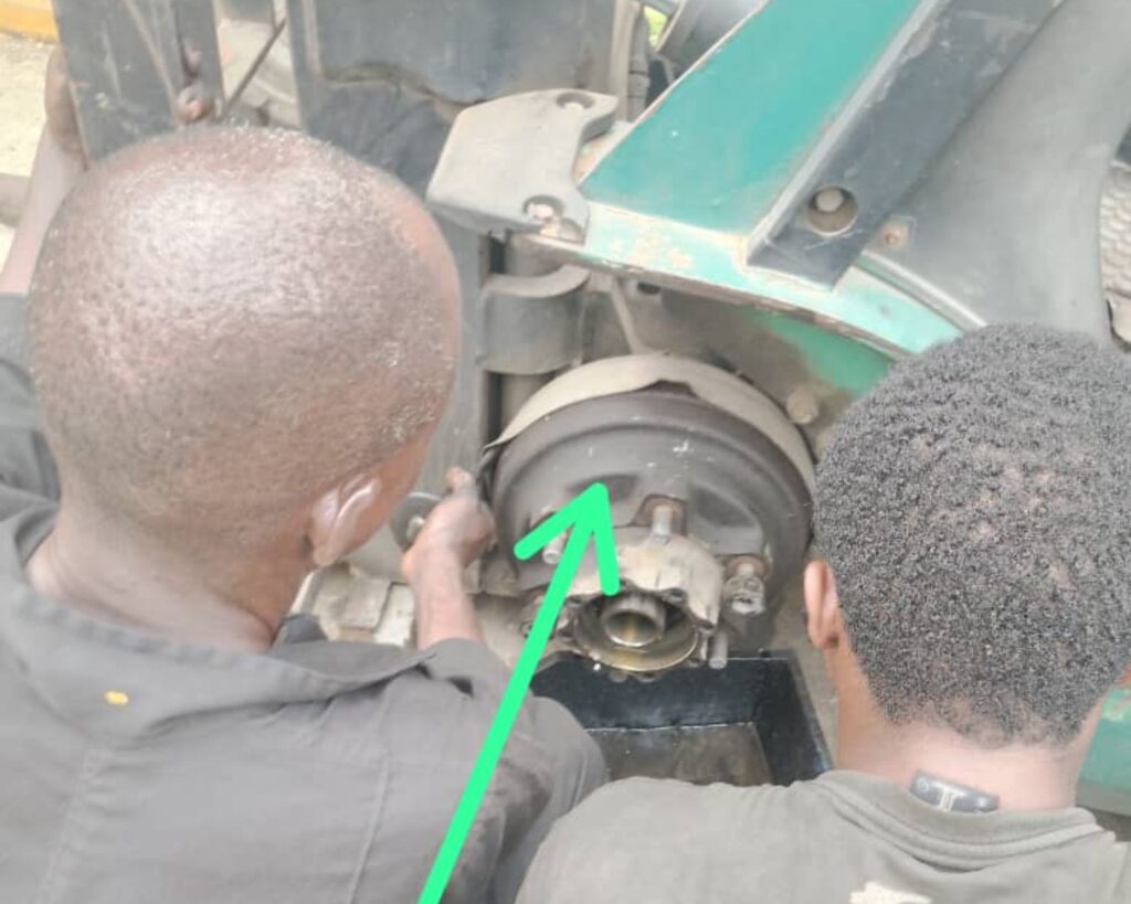 Technicians repairing forklift wheel hub and brake assembly in industrial workshop